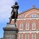 A statue of Samuel Adams with the inscription 1722 through 1803 stands in front of a brick building